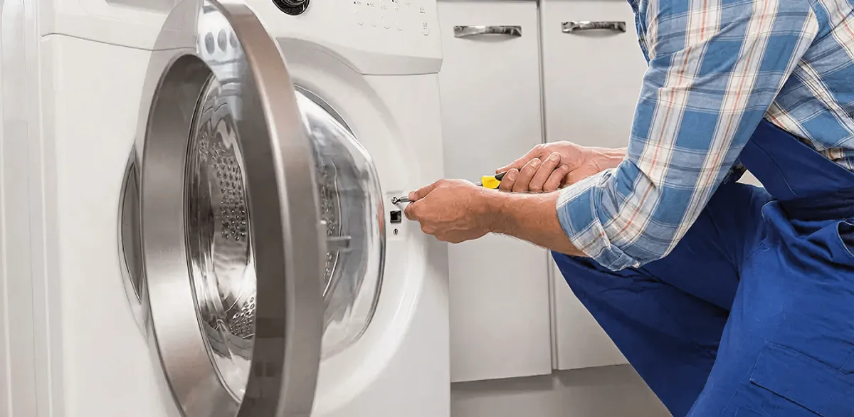 Handyman repairing a clothes dryer and checking electrical connections in Anchorage, AK