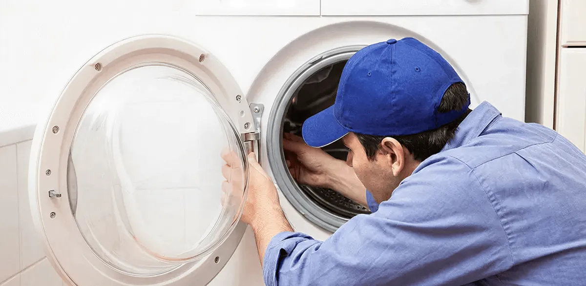 Washing machine repair handyman inspecting a front-load washer drum in Anchorage, AK