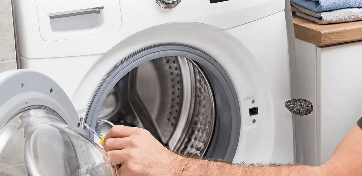 Handyman repairing a front-load washing machine and inspecting the drum in Anchorage, AK